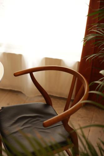 a wooden chair in a room with a plant at K L O S T E R E T - The Luxurious Townhouse of Copenhagen in Copenhagen
