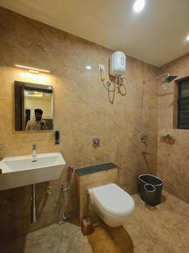 a man taking a picture of a bathroom with a toilet and sink at The Sharva 1 by Shiva stays with open air Bathtub, close to Varca beach in Varca