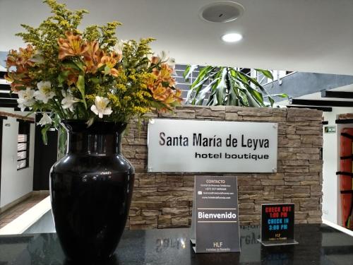 a black vase filled with flowers sitting on a table at Santa Maria de Leyva hotel boutique in Villa de Leyva