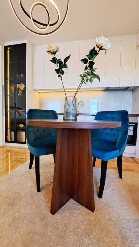 a dining room table with blue chairs and a vase with flowers at Jacuzzi Life in Subotica