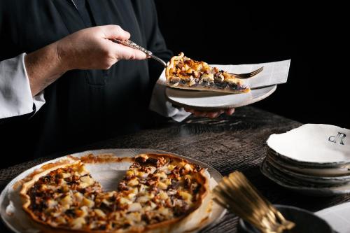 a person holding a slice of pizza on a table at Refugium Lunz in Lunz am See
