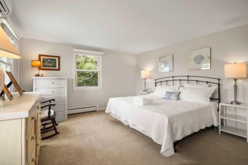 a bedroom with a bed and a dresser and a window at Water Views Walk to Beach Dogs Welcome in Brewster