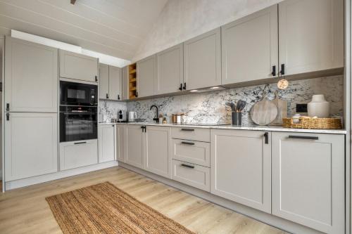 a white kitchen with white cabinets and a wooden floor at Panoramic Sea View Apartment in The Mumbles
