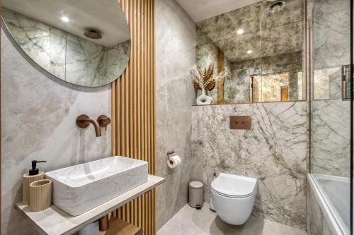 a bathroom with a sink and a toilet and a mirror at Panoramic Sea View Apartment in The Mumbles