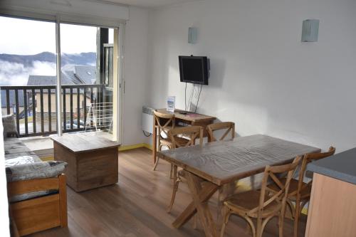 a living room with a table and chairs and a balcony at Résidence Les Adrets de Peyragudes in Germ