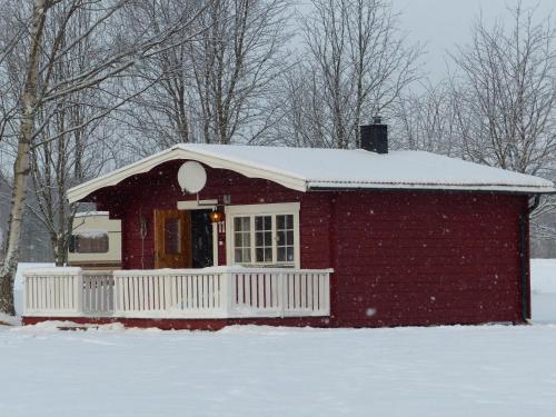 a red house with a white fence in the snow at Björkebo Camping in Stöllet