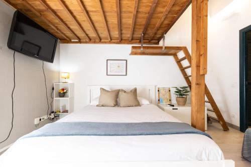 a bedroom with a bed with a tv on the wall at Oli by Unik Vacation in Tarragona