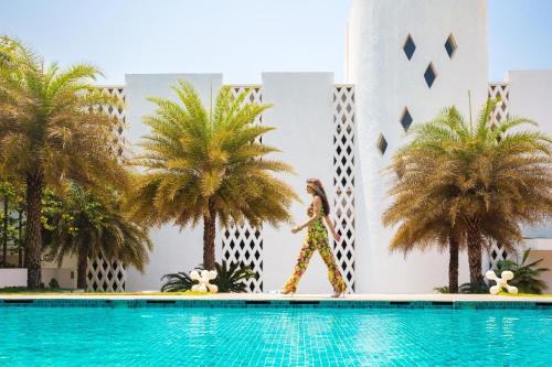 a woman walks by a pool at a hotel at W Goa in Vagator