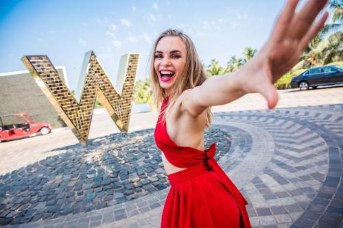 a woman in a red dress standing in front of a sign at W Goa in Vagator
