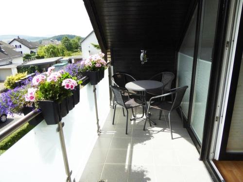 a balcony with a table and chairs and flowers at Helga Willing Comfortable holiday residence in Meschede