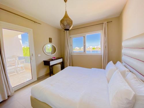 a bedroom with a white bed and a large window at Nayah Stays, Joubal Lagoons flowery apartment in Hurghada