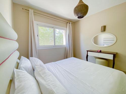 a bedroom with a white bed and a window at Nayah Stays, Joubal Lagoons flowery apartment in Hurghada