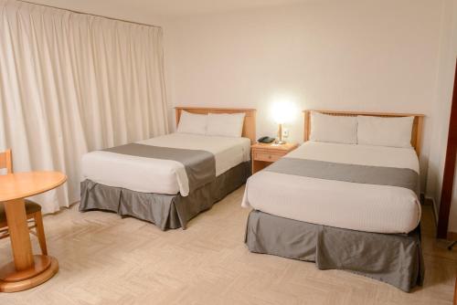 a hotel room with two beds and a table at HOTEL DON MIGUEl in Tapachula