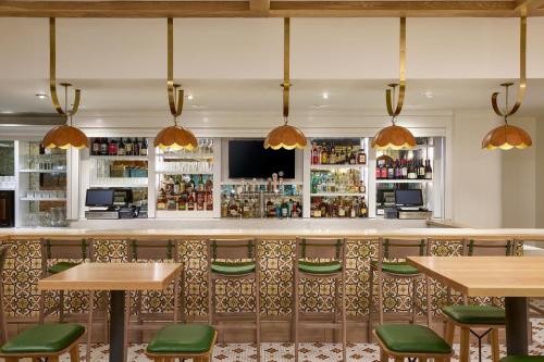 a bar with wooden tables and green chairs at The Westin Oaks Houston at the Galleria in Houston