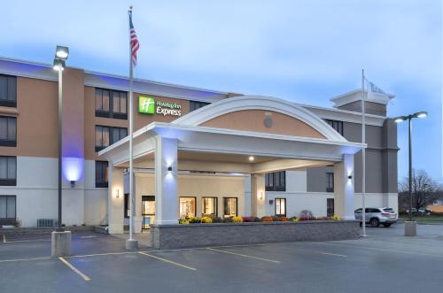a hotel building with a flag in a parking lot at Holiday Inn Express Rochester-Greece in Greece