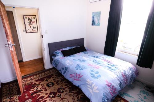 a bedroom with a bed in a room with a window at Nothing Fancy 90s Queen Room in Whanganui