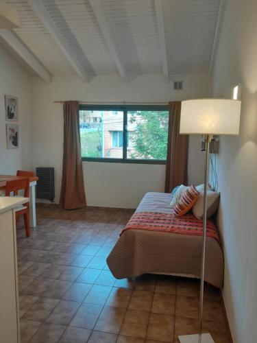 Un dormitorio con una cama con una lámpara y una ventana. en Casita de los Andes, en San Carlos de Bariloche
