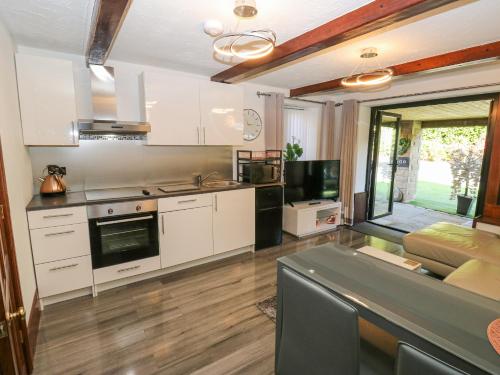 a kitchen with white cabinets and a living room at Moor Cottage in Oldham