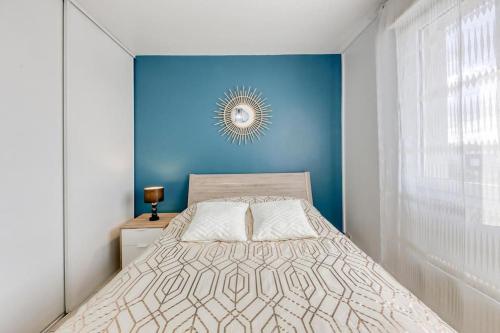 une chambre avec un lit avec un mur bleu dans l'établissement Appartement lumineux Parking proche transport, au Bourget