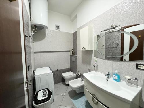 a bathroom with a sink and a toilet and a mirror at Downtown Apartment in Korçë