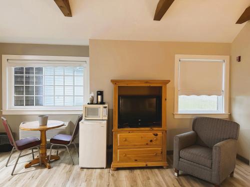 a living room with a television and a table and chairs at Spruce Lane Lodge and Cottages in Smoketown