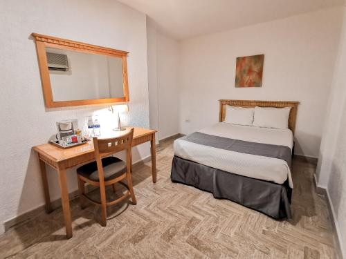 a small hotel room with a bed and a desk at HOTEL DON MIGUEl in Tapachula