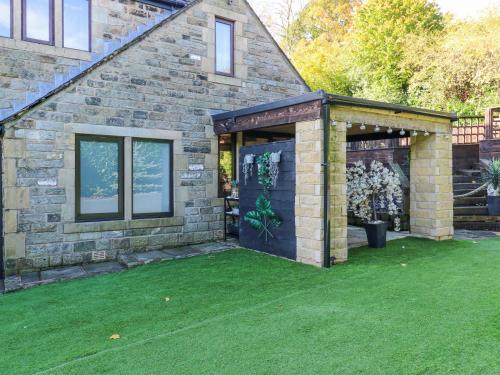 a brick house with a green lawn in front of it at Moor Cottage in Oldham