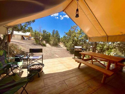 a porch with a bench and a table and chairs at Glamping Tent #7 with AC Heat AC and Private Bath in Orderville