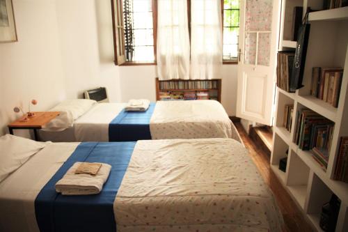 a bedroom with two beds and a book shelf at La Casona, habitación privada con baño en suite in La Plata