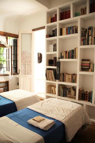 two beds in a room with bookshelves at La Casona, habitación privada con baño en suite in La Plata