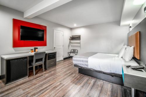 a hotel room with a bed and a desk and a tv at Rodeway Inn South Gate - Los Angeles South in South Gate