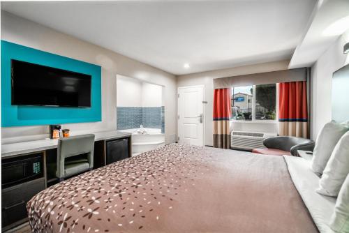 a bedroom with a bed and a flat screen tv at Rodeway Inn South Gate - Los Angeles South in South Gate