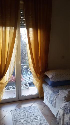 a bedroom with a window with curtains and a bed next to a door at Villa Fiorita in Monfalcone