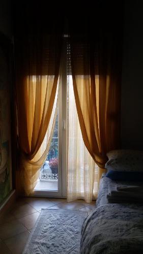 a bedroom with a bed and a window with curtains at Villa Fiorita in Monfalcone