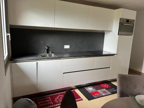une cuisine avec des armoires blanches et un évier dans l'établissement PERRILLAT appart, au Grand-Bornand