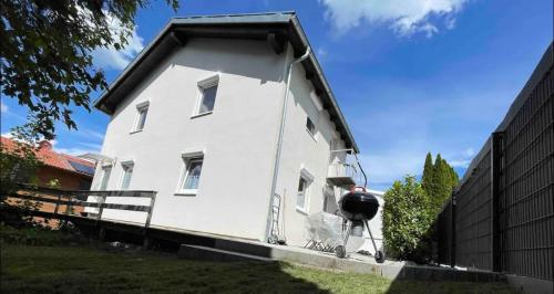 Una pequeña casa blanca al lado de una valla en Einfamilienhaus im 5Seen-Land, en Wörthsee