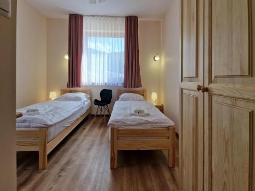 two twin beds in a room with a window at Holiday Home Wi niowa with Pool and Mountains in Iwierzyce