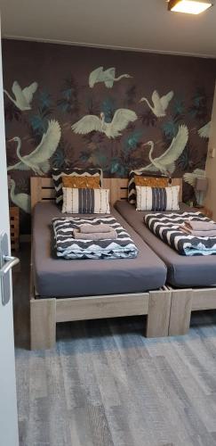 two beds in a room with a wall with birds at JaBaKi Garden House in Hoofddorp