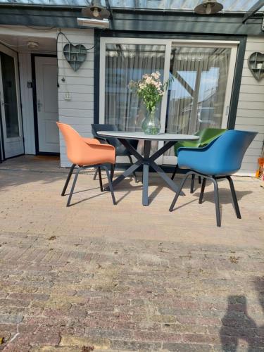 a table with three chairs and a vase of flowers at JaBaKi Garden House in Hoofddorp