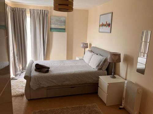 a bedroom with a bed with a lamp and a window at Cardiff Bay, City centre apartment in Cardiff