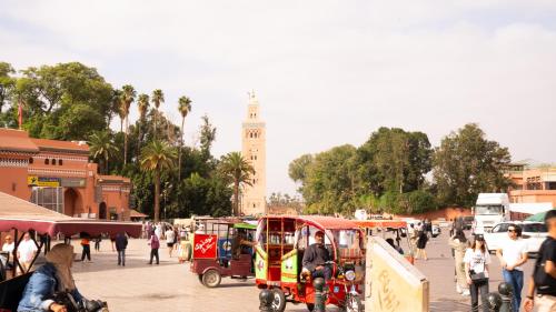 a group of people walking around a street with a clock tower at Riad Allal in Marrakech