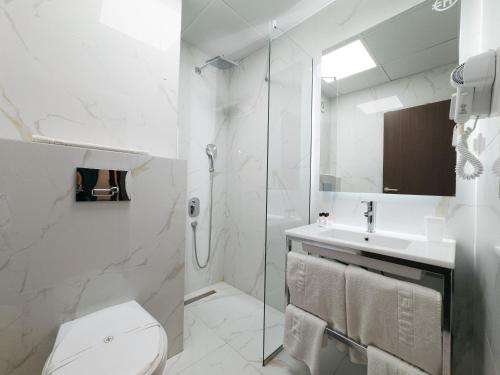 a white bathroom with a toilet and a sink at Hotel Gradche in Kochani