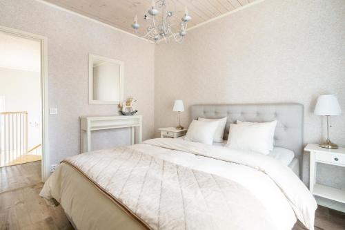 a bedroom with a large white bed with a chandelier at Luxurious Villa Snow with Jacuzzi in Rovaniemi
