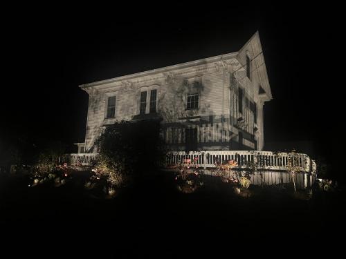 an old house with a fence in front of it at night at Yardarm Motel in Searsport