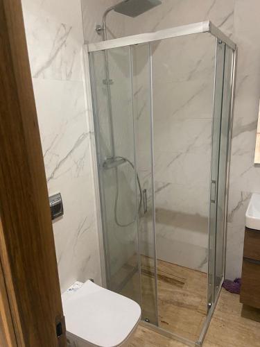 a bathroom with a glass shower with a toilet at Swim and rest in Beni Touzine
