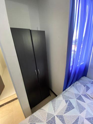 a bedroom with a black cabinet and blue curtains at Santa Fe Relax in Santa Fe de Antioquia