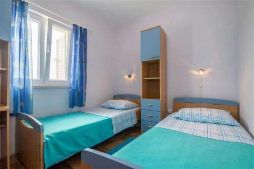 Dos camas en un dormitorio con cortinas azules. en Apartment Mer, en Sevid