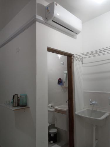 a white bathroom with a sink and a toilet at Loft10 COMPLETO AR CANAIS ASSINAT GARAGEM INTERNET prox Aparecida e Industrias in Pindamonhangaba