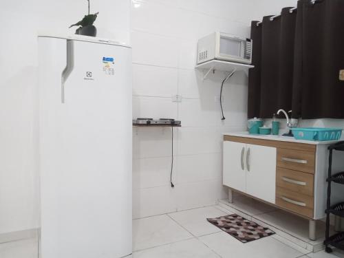 a kitchen with a refrigerator and a microwave at Loft10 COMPLETO AR CANAIS ASSINAT GARAGEM INTERNET prox Aparecida e Industrias in Pindamonhangaba