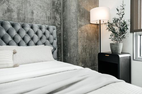 a bed with a tufted headboard and a lamp at Hollywood Designer Apartment in Los Angeles